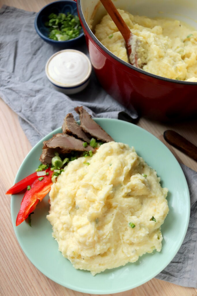 creamy garlic baked dutch oven mashed potatoes on a blue plate and wooden table