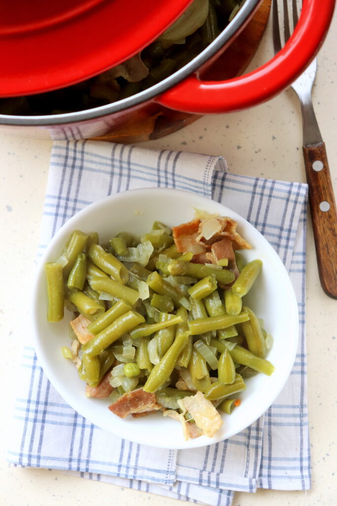 Dutch oven filled with green beans and crispy bacon pieces