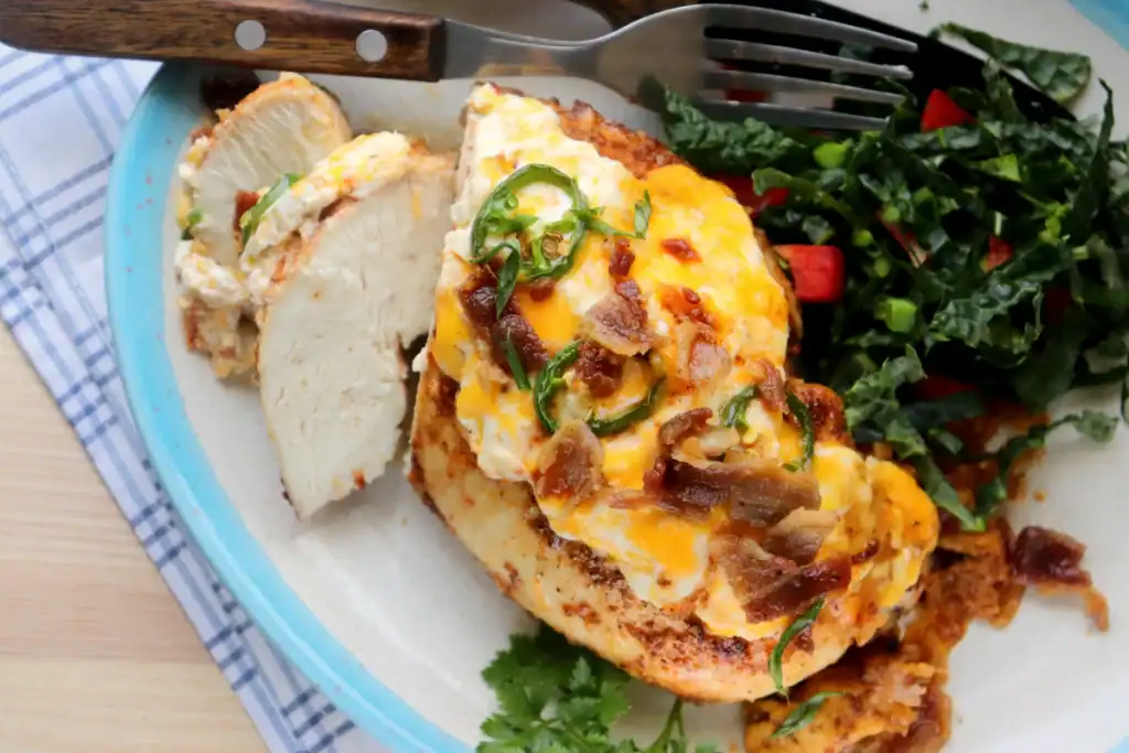 a serving of juicy dutch oven cooked chicken with jalapenos, cheese, and crumbled bacon with shredded kale