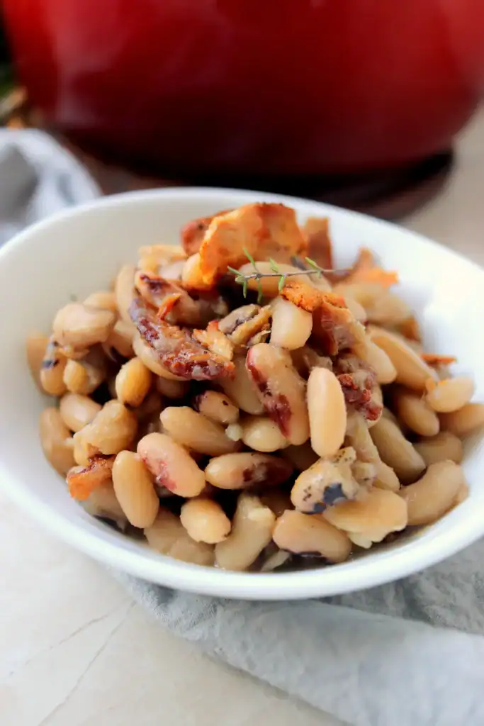 Close up of tender black eyed peas and bacon in a Dutch oven, ready to serve.