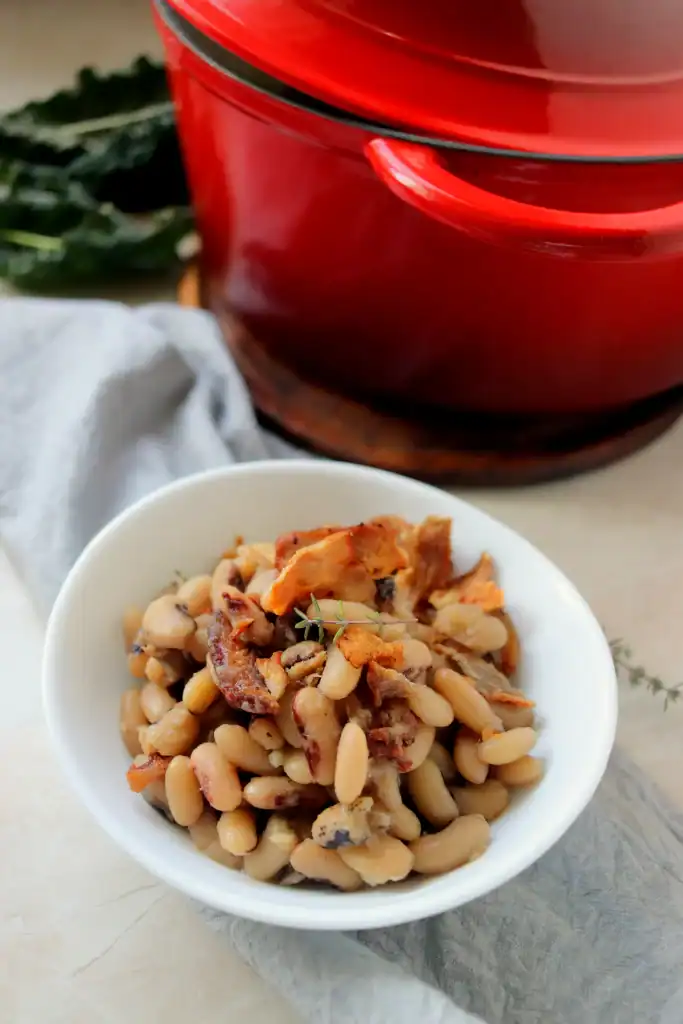 A serving of black eyed peas with chopped bacon in a rustic Dutch oven.