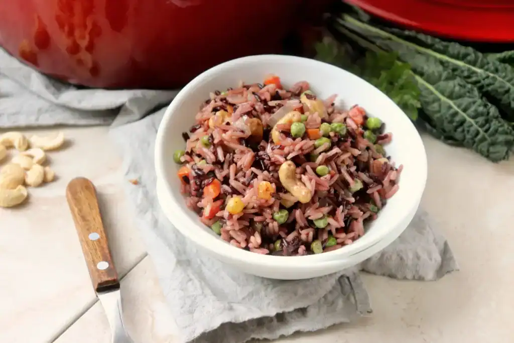 Side view of a spoon scooping rice pilaf with toasted cashews