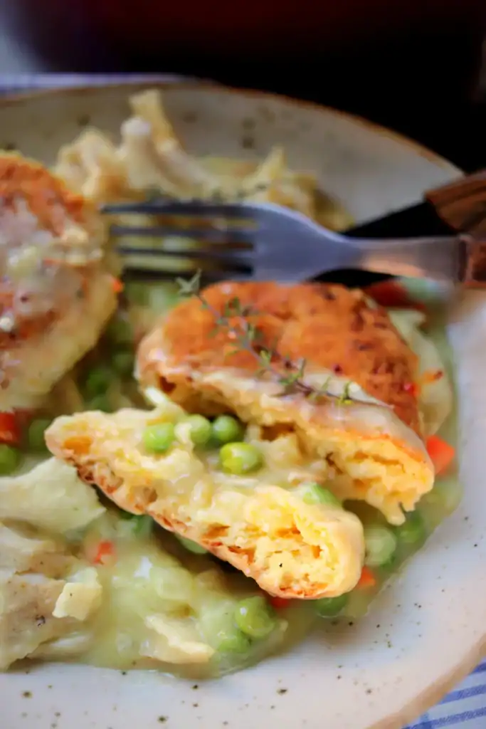 Sliced chicken pot pie being served from a Dutch oven with vegetables and rich gravy.