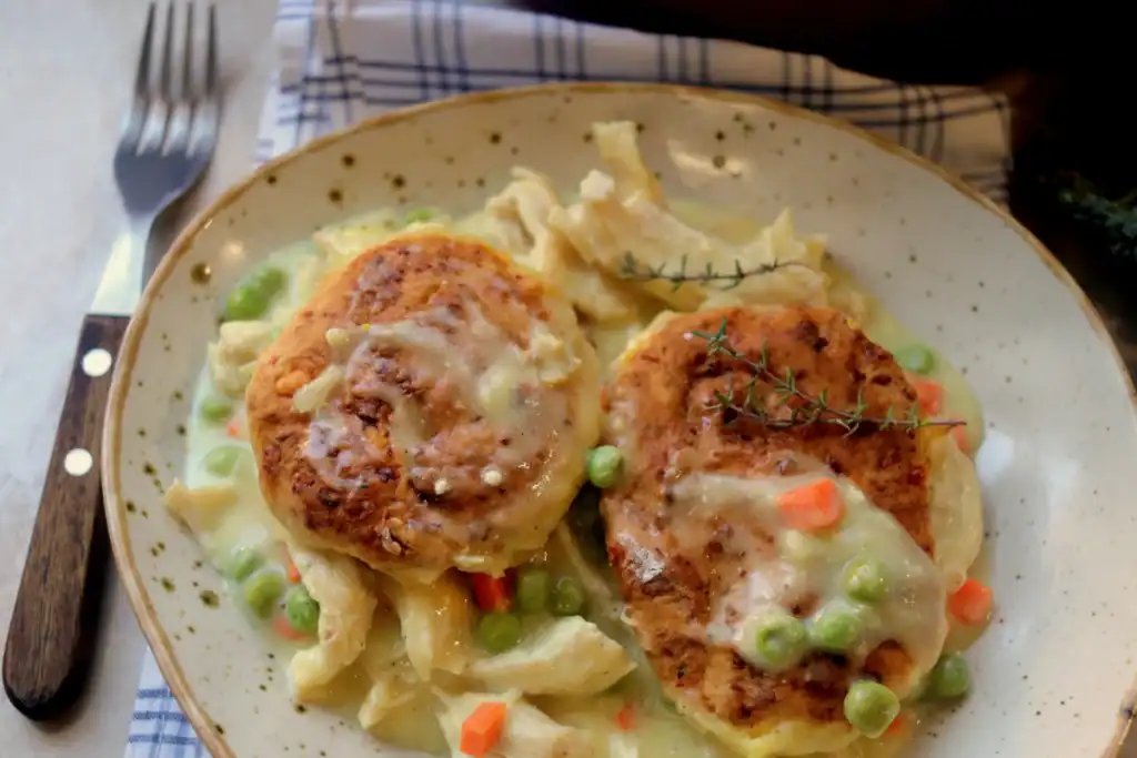 Close-up of chicken pot pie filling with tender chicken, carrots, and peas in a creamy sauce.


