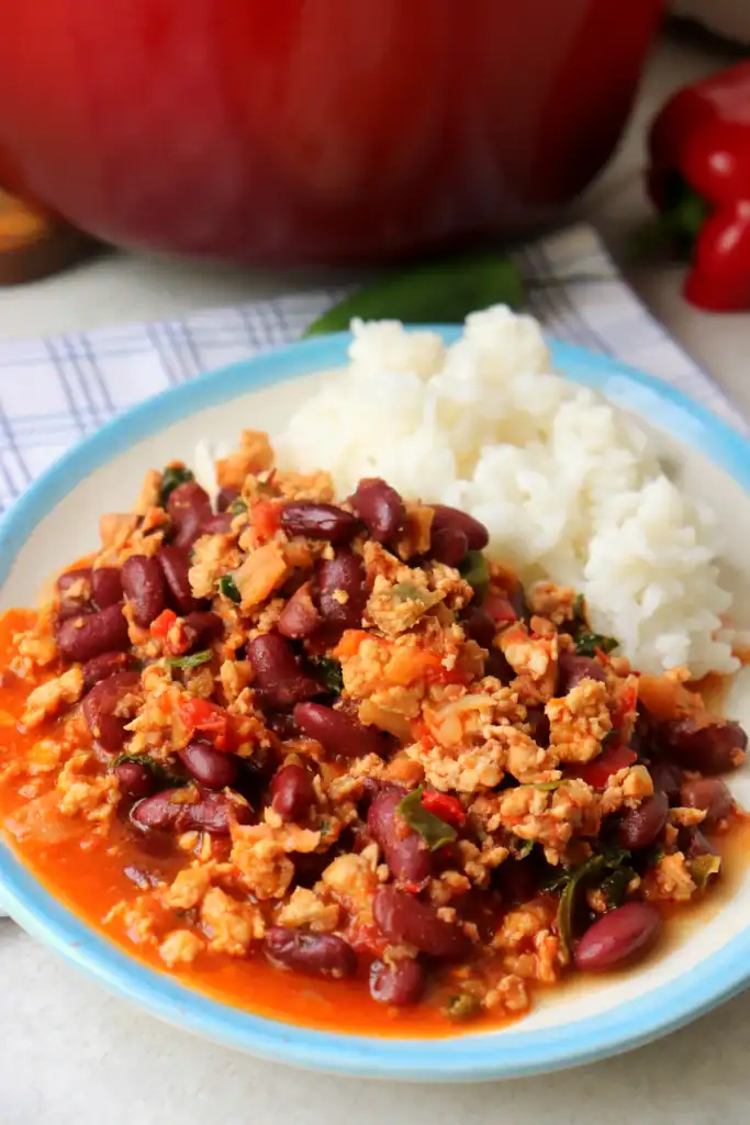 a fresh bowl of cooked white rice with homemade dutch oven chili on a white plate with a blue rim