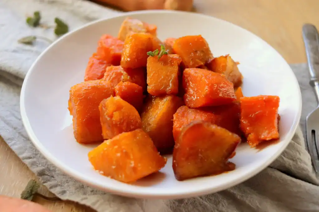 Close up of tender sweet potatoes with a golden brown sugar glaze in a Dutch oven.
