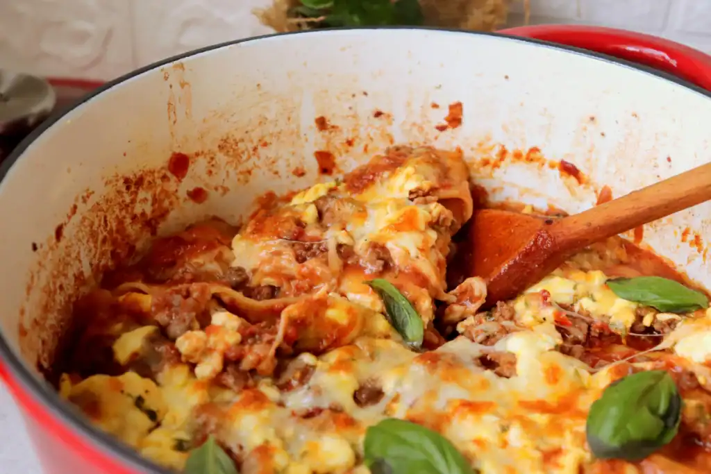 One pot lasagna baked in a Dutch oven with rich sauce and gooey cheese layers.

