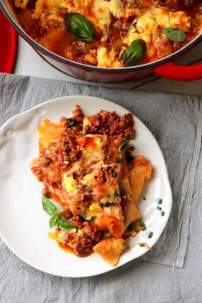 Cheesy Dutch oven lasagna sliced and ready to serve from the pot.