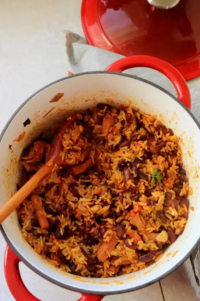Dutch oven filled with red beans, sausage, and rice in a rich, savory sauce.