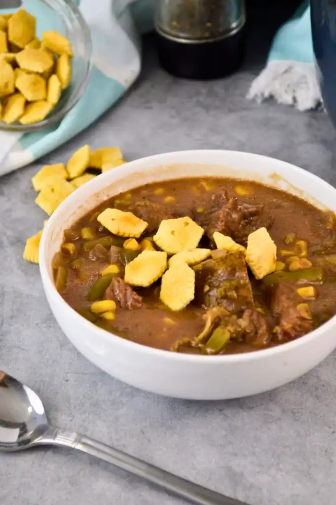 Close-up of smoky beef chunks, potatoes, and carrots simmered in a Dutch oven.