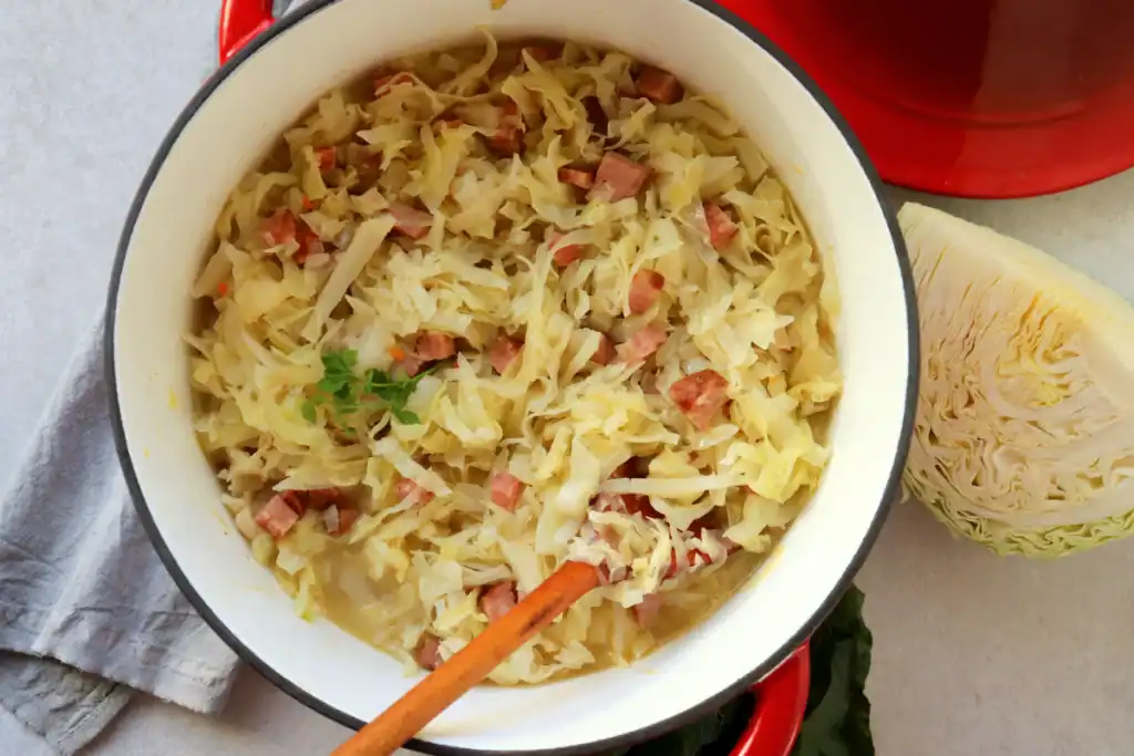 Southern cabbage being served from a Dutch oven, golden and tender.