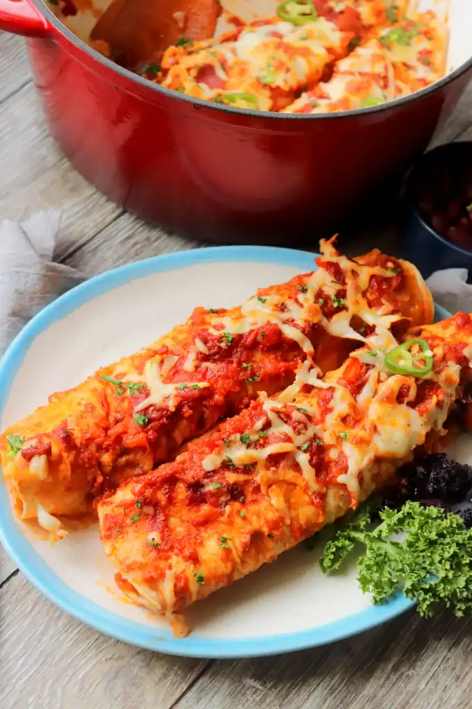 Cheesy veggie enchiladas baked in a Dutch oven, garnished with cilantro.

